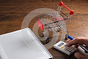 Budget calculation. Man calculates the budget. Shopping cart a on table with calculator and paper. Budget of poor and low income