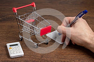 Budget calculation. Man calculates the budget. Shopping cart a on table with calculator and paper. Budget of poor and low income