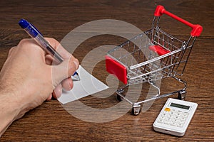 Budget calculation. Man calculates the budget. Shopping cart a on table with calculator and paper. Budget of poor and low income