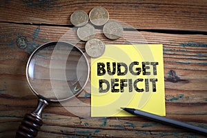 Budget Deficit. Euro cash and magnifying glass on a wooden background