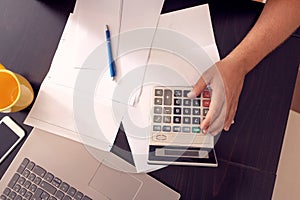 Budget planning - stressed man writing home budget with calculator top view