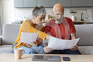 Budget Planning. Worried Senior Spouses Holding Papers And Calculating Family Spends Together