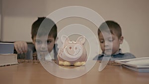 Budgeting and children savings. Two brothers counting money. Younger one hides under the table. Selective focus, slow