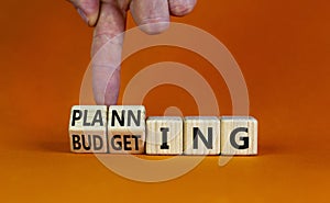 Budgeting and planning symbol. Businessman turns wooden cubes and changes the word planning to budgeting. Beautiful orange