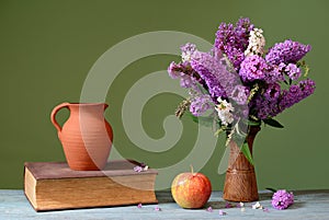 Budleja in a ceramic vase, apple and books photo