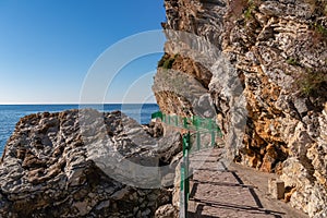 Budva - Idyllic walk along steep high cliffs to the central beach Mogren of coastal tourist city of Budva, Montenegro