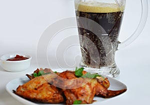 buffalo chicken wings barbecue or grill with red sauce in a gravy boat, beer in a tall glass with foam on a white