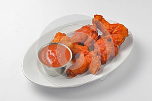 Buffalo chicken wings with tomato dip sauce. Served on a white plate over white background