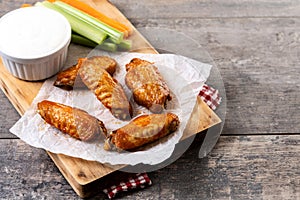 Buffalo spicy chicken wings with cayenne pepper sauce on wooden table