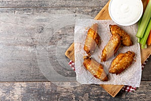 Buffalo spicy chicken wings with cayenne pepper sauce on wooden table