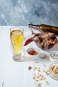 Buffalo style chicken wings served with cold beer on white wood background
