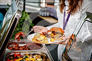 Buffet breakfast at the hotel. Guest with a burger on a plate.