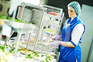 Buffet female worker servicing food in cafeteria