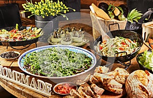 Buffet with a large selection of vegetable dishes and salads and Italian bread, healthy food