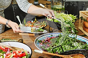 Buffet with a large selection of vegetable dishes and salads, woman picks salad in a plate, healthy food