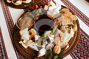 Buffet with a plate of appetizers of different varieties of cheese, fruits, sauces, crackers, embroidered cloth, Ukrainian traditi