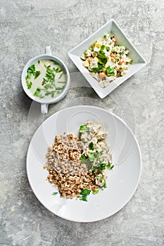 Buffet restaurant, menu option, beef Stroganoff, green salad and chicken soup. Gray background, top vie