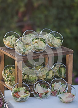 Buffet salad in a glass plate on a wooden stand