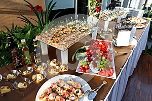 Buffet table full of food in small dishes and a fruit platter. photo