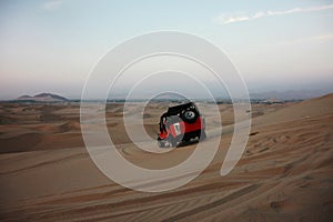 A buggie that is riding over the sand dunes in the desert nearby Ica in Peru with tourists
