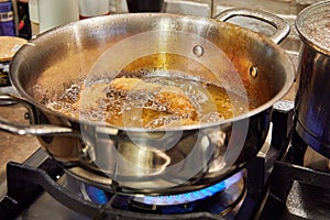 Bugnes, French donuts in boiling oil in saucepan photo