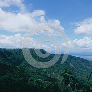 Buidings and towers on top of a green mountain with blue sky and white clouds at Tagaytay, Philippines