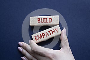 Build empathy symbol. Wooden blocks with words Build empathy. Psychologist hand. Beautiful deep blue background. Psychology and