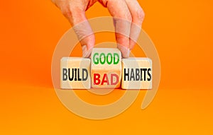 Build good or bad habits symbol. Concept word Build good or bad habits on wooden cubes. Businessman hand. Beautiful orange table