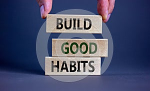 Build good habits symbol. Wooden blocks with words `build good habits`. Male hand. Beautiful grey background, copy space. Busine