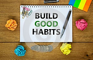 Build good habits symbol. Words `Build good habits` on white note. Wooden table, colored paper, paper clips, pen, coins. Busines