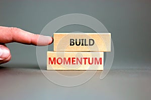 Build momentum symbol. Concept words Build momentum on wooden blocks. grey table grey background. Businessman hand.