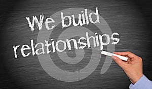 We build relationships - female hand with chalk writing text photo