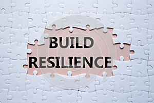 Build resilience symbol. White puzzle with words Build resilience. Beautiful pink background. Business and Build resilience