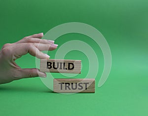 Build trust symbol. Wooden blocks with words Build trust. Beautiful green background. Businessman hand. Business and Build trust