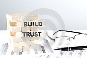 BUILD TRUST is written on wooden blocks on a chart background