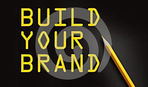 BUILD YOUR BRAND words on black with yellow pencil besides. Branding rebranding marketing business startup concept