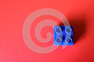 Buildable blue plastic block on a red background. Concept of loneliness and social isolation reduces cognitive skills which can le