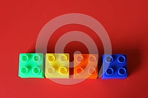 Buildable colored plastic blocks to play, build and organize on a red background as a concept of inclusion, diversity and pluralit