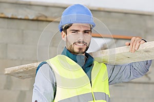 builder and apprentice carrying wood on construction site