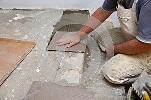 The builder arranges ceramic tiles on the stairs inside the building.