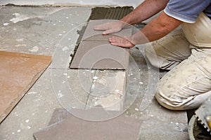 The builder arranges ceramic tiles on the stairs inside the building.