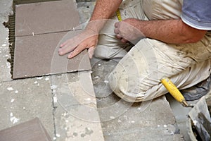 The builder arranges ceramic tiles on the stairs inside the building.