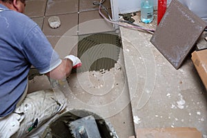 The builder arranges ceramic tiles on the stairs inside the building.