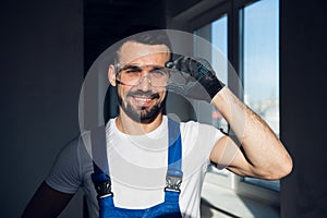 Builder in blue overalls and goggles smiling