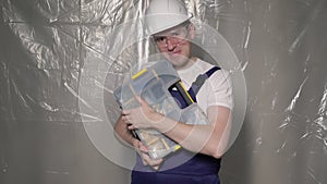 Builder in blue overalls and white hard hat helmet and glasses with toolbox.