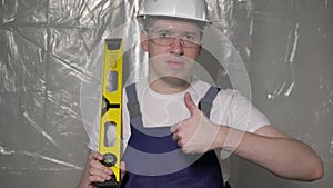 Builder in blue overalls and white hard hat helmet and protective glasses.