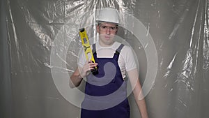 Builder in blue overalls and white hard hat helmet and protective glasses.