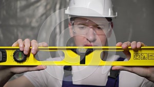 Builder in blue overalls and white hard hat helmet and protective glasses.