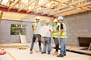 Builder On Building Site Looking At Plans With Apprentices photo