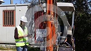 Builder at building site wearing work helmet and reflecting jacket use tablet for test and checking.